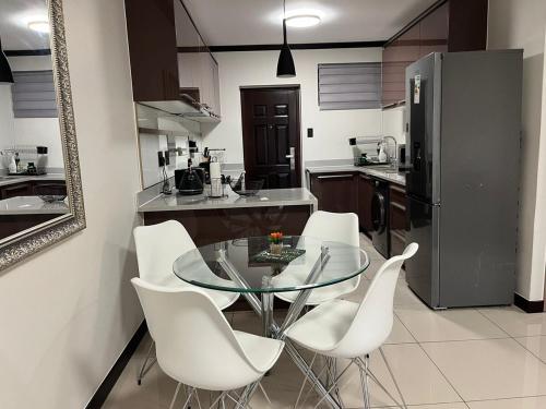 a kitchen with a glass table and white chairs at Ambience Defined in Randjesfontein