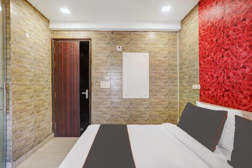 a bedroom with a bed and a red wall at Collection O Model Town Metro View in New Delhi
