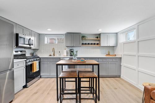 eine Küche mit grauen Schränken und einem Tisch mit Stühlen in der Unterkunft Urban Hideaway - Charming 2 Bedroom Apartment Close to Denver's Best Attractions in Denver