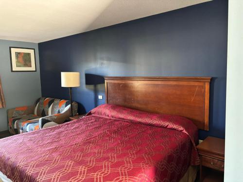 a bedroom with a red bed and a blue wall at Budget Inn Express in Augusta