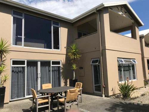 a house with a table and chairs in front of it at Beautiful 3 bedroom apartment, only steps to the golden sand in Kaiteriteri
