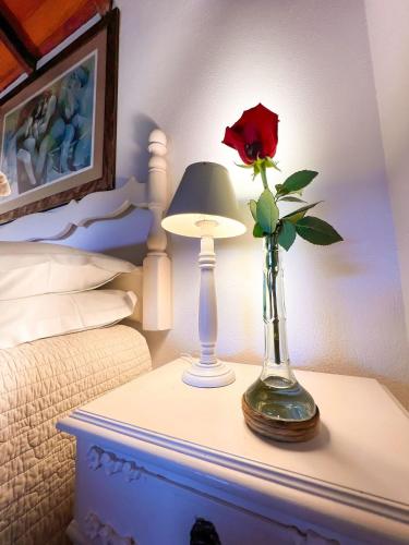 a flower in a vase on a table next to a lamp at Pousada Borghetto – Charme e Exclusividade no Vale dos Vinhedos in Bento Gonçalves