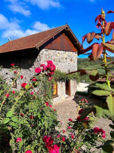 a stone house with red flowers in front of it at Pousada Borghetto – Charme e Exclusividade no Vale dos Vinhedos in Bento Gonçalves