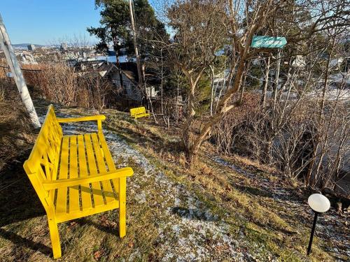 a yellow bench sitting on the side of a street at Fantastic apartment with garden and sea view on Bygdøy in Oslo