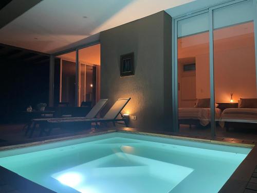 a swimming pool in a room with a living room at Casa en Vistalba para dos personas con yacuzzi de temporada en la terraza in Ciudad Lujan de Cuyo