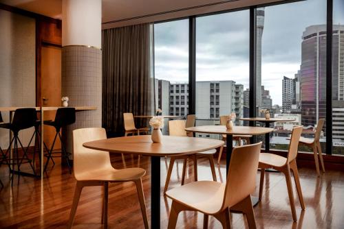 a restaurant with tables and chairs and large windows at Grand Millennium Auckland in Auckland
