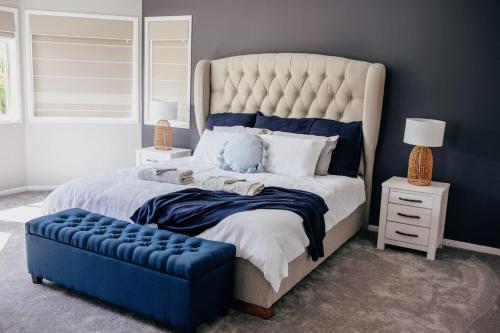 a bedroom with a large bed and a blue ottoman at Riverside Retreat Pool, Pontoon & Space in Gold Coast