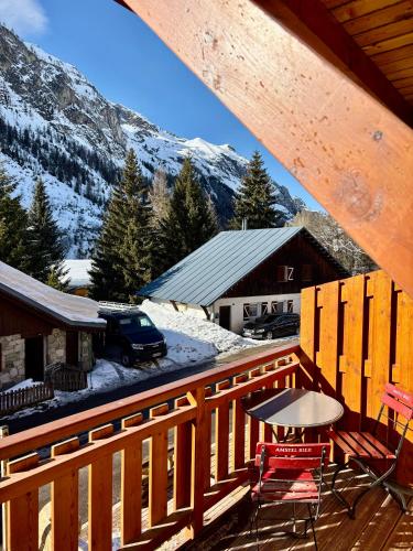 une terrasse avec une table et des chaises ainsi qu'une montagne enneigée dans l'établissement Appartement moderne et entièrement rénové en plein cœur du village, chambre séparée, balcon vue montagne, très proche des pistes, à Tignes