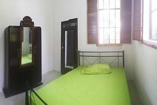una camera da letto con un letto verde e uno specchio di House Colonial Style a La Hatte