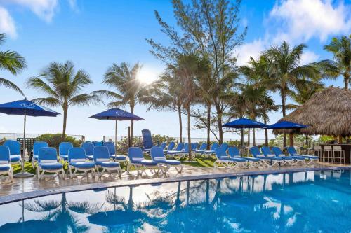 a pool with chairs and umbrellas and palm trees at Marenas Beach Resort in Miami Beach