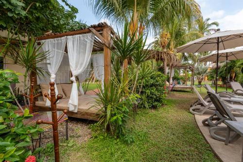 a bed in a garden with chairs and an umbrella at Rojo Manglar Acapulco in Acapulco
