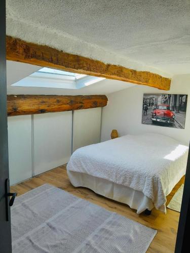 une chambre avec un lit blanc et une lucarne dans l'établissement Petit nid perché très cosy au centre de Béziers, à Béziers