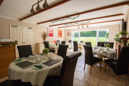 a dining room with tables and chairs and a room with at Lovesgrove Country Guest House in Pembroke Dock