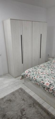 a bedroom with white cabinets and a bed with a blanket at C&C apartamente in Sîngeorgiu de Mureş