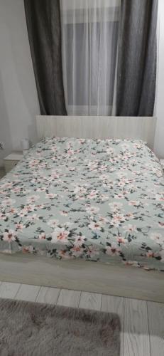 a bed with a blanket with flowers on it at C&C apartamente in Sîngeorgiu de Mureş