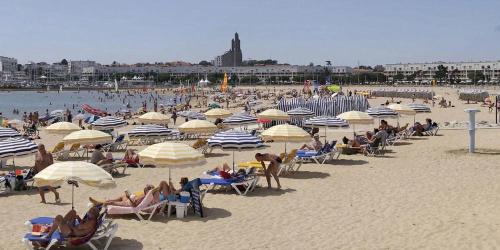 un groupe de personnes assis sous des parasols sur une plage dans l'établissement Appartement 3 pièces ROYAN - Centre Ville, à Royan