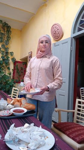 a woman holding a plate of food on a table at La Maison Haute Larache Morocco in Larache