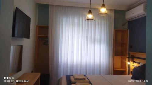a bedroom with a bed and a white curtain at Gökçeada Helios Pansiyon in Gokceada Town
