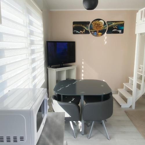 une salle à manger avec une table noire et une télévision dans l'établissement Studio Cosy, à Saintes