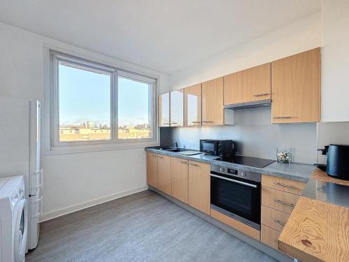 une cuisine avec des placards en bois et une grande fenêtre dans l'établissement Appartement Le balcon, à Dunkerque