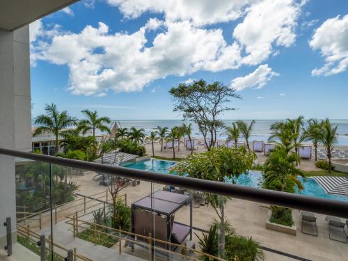 a view of the pool and beach from the balcony of a resort at Playa Caracol Apt with Radisson Hotel Amenities in El Quindio