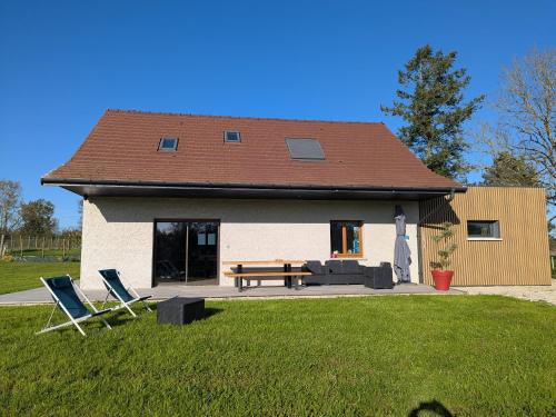 a house with two lawn chairs and a picnic table at Gite les Caravottes 4 Etoiles avec Jacuzzi - JURA in Courlaoux