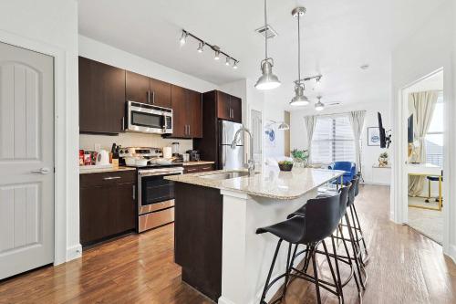 a kitchen with wooden cabinets and a island with bar stools at Big and Spacious 1B with Pool Near Toyota HQ The Star Legacy West in Frisco