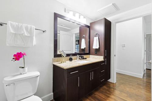 a bathroom with a toilet and a sink and a mirror at Big and Spacious 1B with Pool Near Toyota HQ The Star Legacy West in Frisco