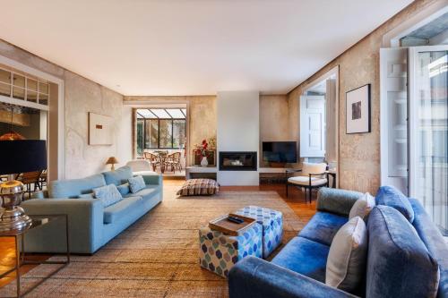 a living room with blue couches and a tv at Pool & Garden Apt In the Heart of Lisbon in Lisbon