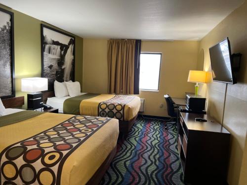 a hotel room with two beds and a flat screen tv at Super 8 by Wyndham Farmington in Farmington