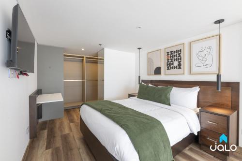 a bedroom with a bed with a green blanket on it at Edificio Taj 97 By Jalo in Bogotá