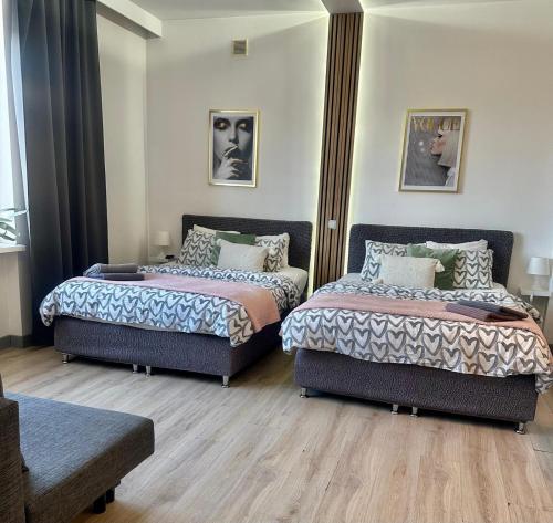 two beds in a room with wooden floors at Exclusive Apartments Smolna in Warsaw
