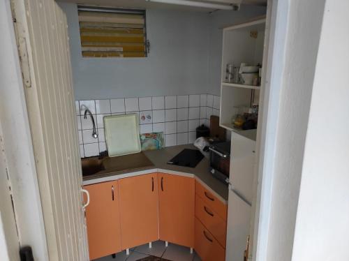 a small kitchen with orange cabinets and a sink at Gite Oiseau du Paradis in Le Marin