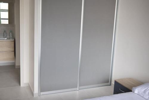 a bedroom with a large glass closet with a bed at Le Soleil de Queenstone in Papeete