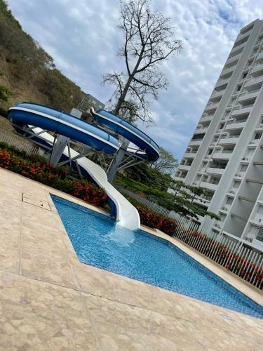 a slide in a swimming pool next to a building at Luxury Apartment Citadela de Sole Santa fe de Antioquia in Santa Fe de Antioquia