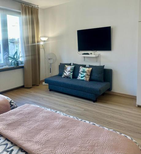 a living room with a blue couch and a flat screen tv at Exclusive Apartments Smolna in Warsaw