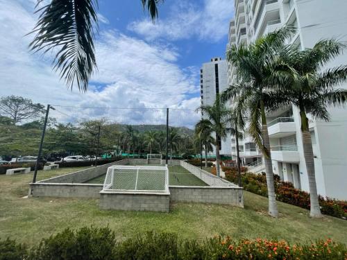 a park in front of a building with palm trees at Luxury Apartment Citadela de Sole Santa fe de Antioquia in Santa Fe de Antioquia