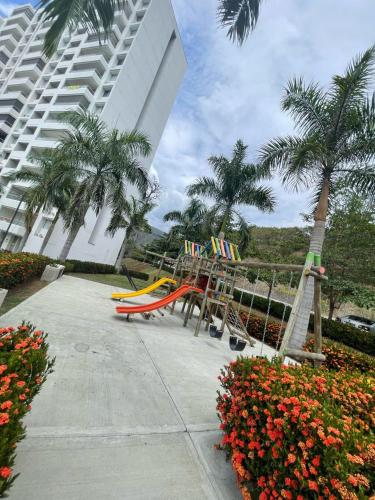 a playground in front of a building with palm trees at Luxury Apartment Citadela de Sole Santa fe de Antioquia in Santa Fe de Antioquia