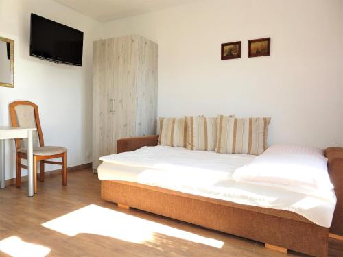 a bedroom with a bed and a tv on the wall at Elizabeth Łeba - Domki Letniskowe & Studia in Łeba