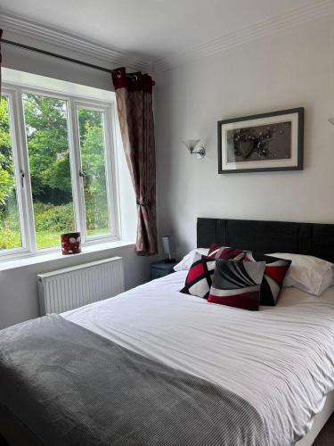 a bedroom with a large bed with two windows at Art Deco One Bedroom Guest Apartment in Yapton