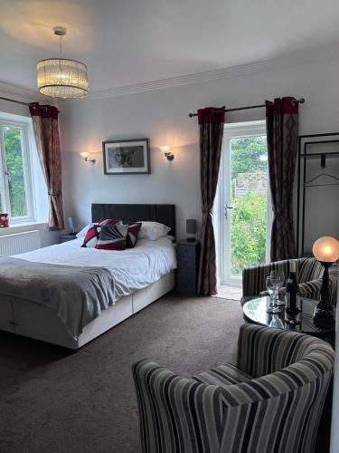 a bedroom with a bed and a chair and windows at Art Deco One Bedroom Guest Apartment in Yapton