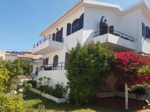 a white house with flowers in front of it at Equinoxea in Nazaré