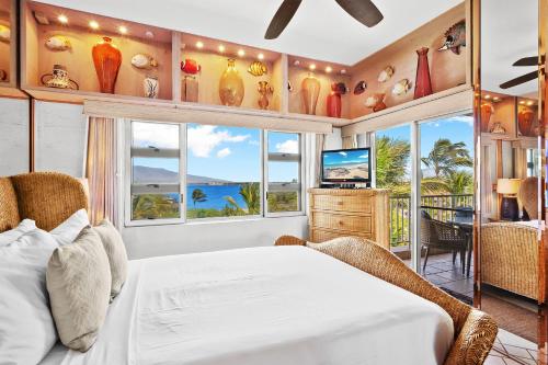 a bedroom with a bed and a view of the ocean at Menehune Shores 606 in Kihei