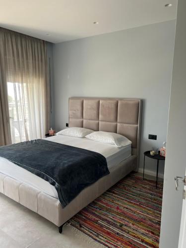 a large bed in a bedroom with a large window at D'azur Home in Vlorë