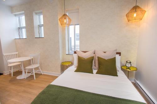 a bedroom with a large white bed with green pillows at Studio #18 - Self Check-In - Plateau - St-Denis in Montreal