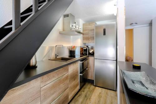 une cuisine avec un réfrigérateur en acier inoxydable et des armoires en bois dans l'établissement Sublime appartement calme et cosy, à Saint-Raphaël