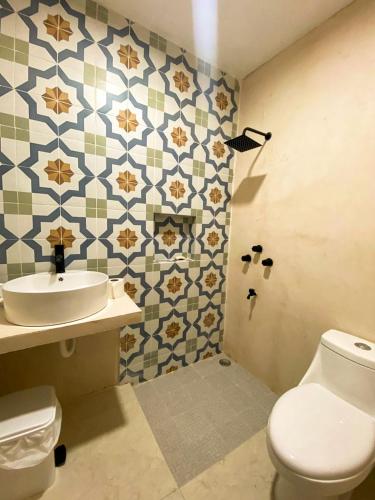 a bathroom with a toilet and a sink at Casona de la Guayabera Hospedaje in Tekit