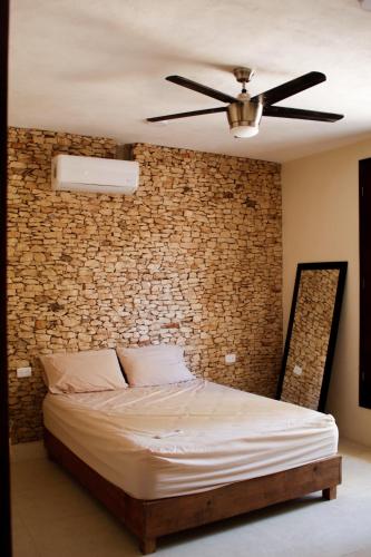 a bed in a room with a brick wall at Casona de la Guayabera Hospedaje in Tekit