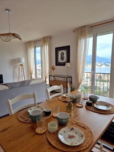 een eettafel met borden en kommen erop bij Appartement Ajaccio vue mer in Ajaccio