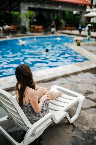 a woman sitting in a chair in front of a swimming pool at Colina de Montalva in Tarapoto